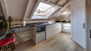 Una cocina moderna con tragaluz, electrodomésticos integrados y techo de madera.