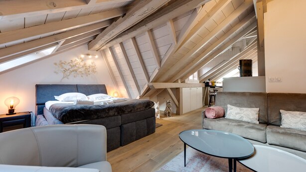 Un dormitorio estilo loft acogedor con una cama grande, un sofá y una mesa de comedor.