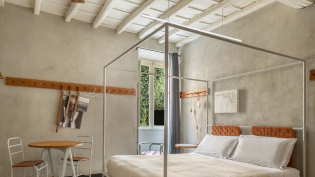 Ein Schlafzimmer mit einem Himmelbett, einem kleinen Tisch mit Stühlen und einem Fenster mit Blick auf Grünflächen.