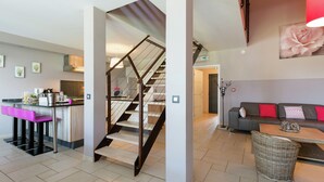 A modern interior with a kitchen, dining area, and a staircase leading to another level. - Magnificent Character Cottage with Spa Tub near Marche-en-Famenne (Marche-en-Famenne)