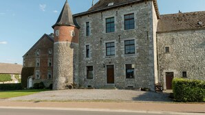 A historic stone building with a central tower and multiple windows. - Magnificent Character Cottage with Spa Tub near Marche-en-Famenne (Marche-en-Famenne)