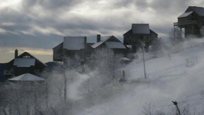 A snowy landscape with several houses, some with steep roofs, and a large water tower structure. - Luxury Condo  in Spectacular  Sugar Mountain  North Carolina (Sugar Mountain)