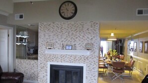 A living room with a fireplace, a clock, and a dining area with chairs and a table. - Luxury Condo  in Spectacular  Sugar Mountain  North Carolina (Sugar Mountain)