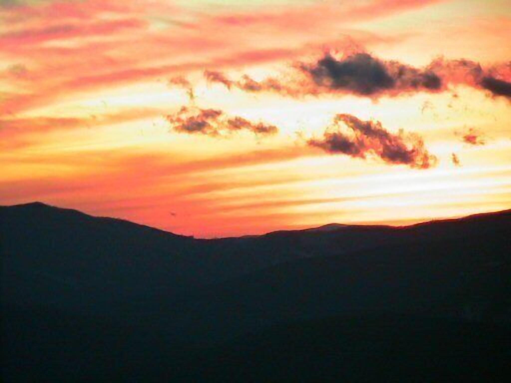 A sunset over a mountain range with clouds.