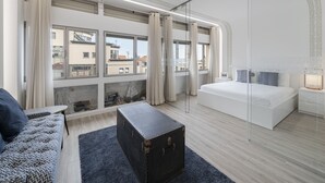 Une chambre d’hôtel moderne avec une grande fenêtre, un canapé, un lit et une petite table.