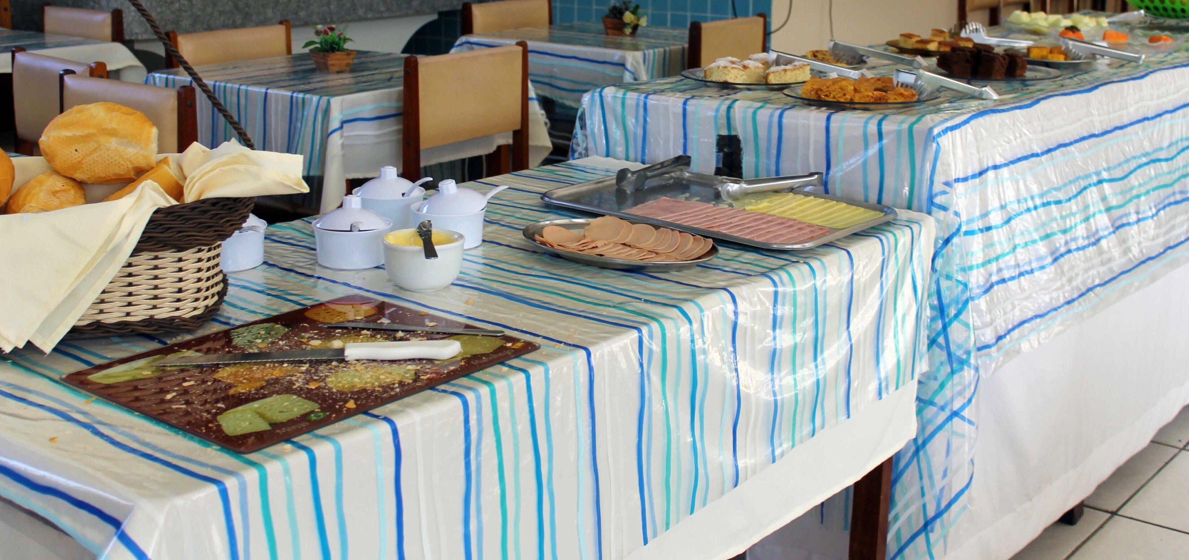 A buffet setup with various food items and serving utensils on tables covered with striped tablecloths.
