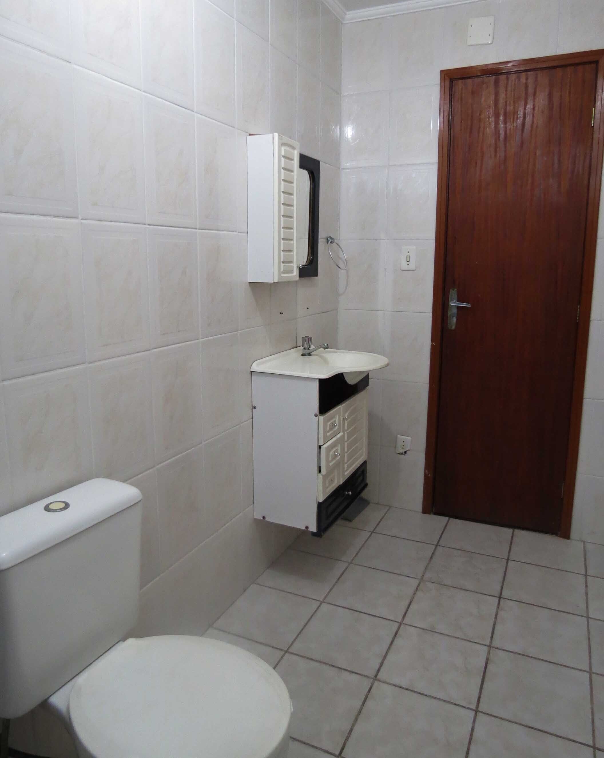 A small bathroom with a toilet, a sink, and a cabinet.