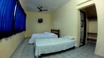 A room with two beds, a ceiling fan, and a small TV on the wall.