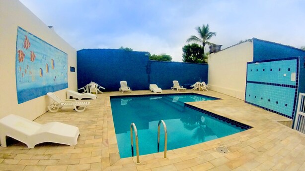 An indoor swimming pool with lounge chairs and a tiled deck. - Hotel Harmonia (Praia Grande)