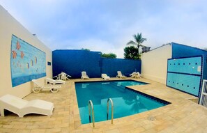 Une piscine intérieure dotée de chaises longues et d’une terrasse carrelée.