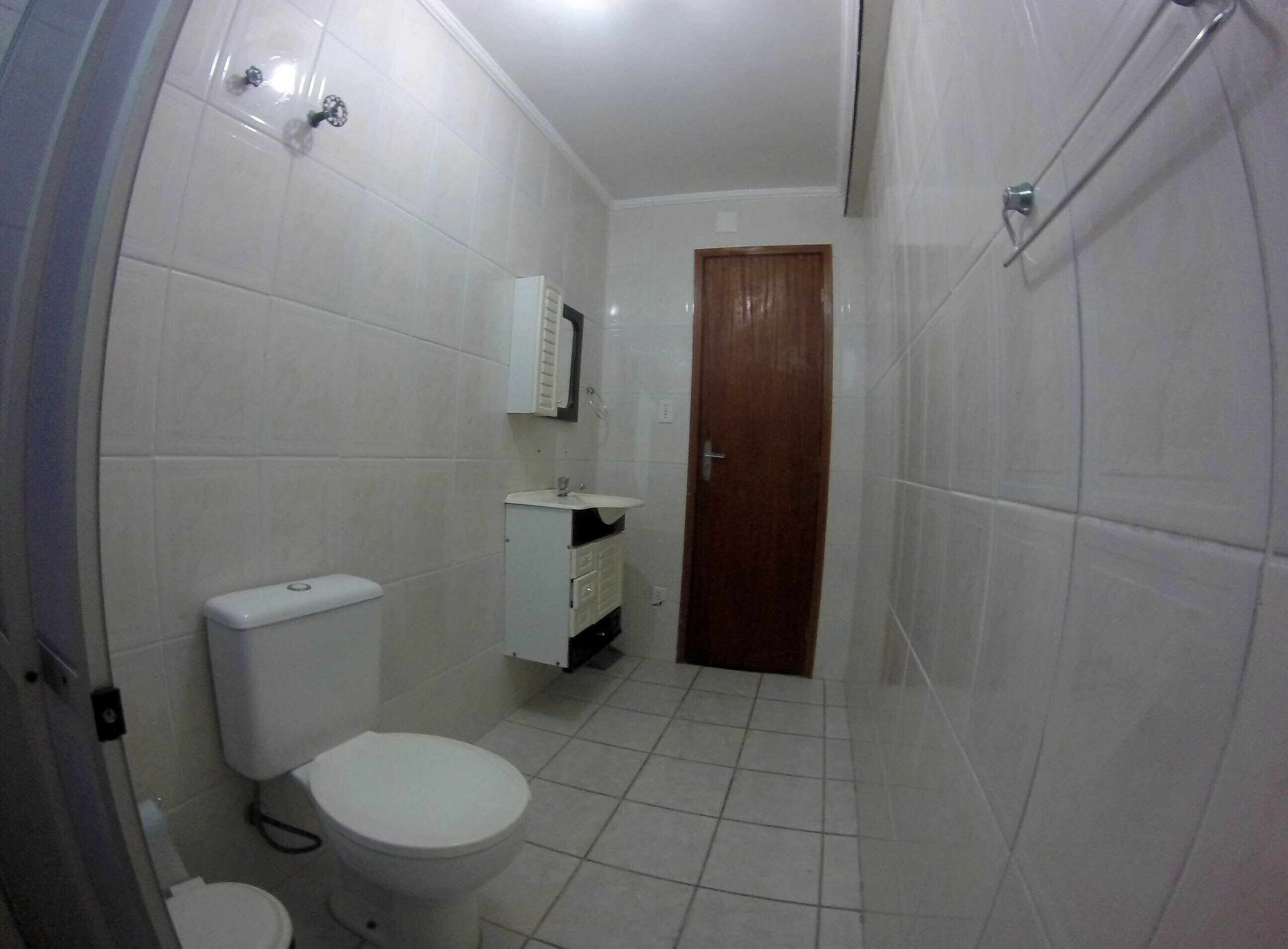 Et lille badeværelse med fliser, toilet, vask og spejl.