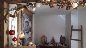 Una habitación rústica con techo de madera, un árbol de Navidad y diversas decoraciones, entre ellas, un farol y figuritas.