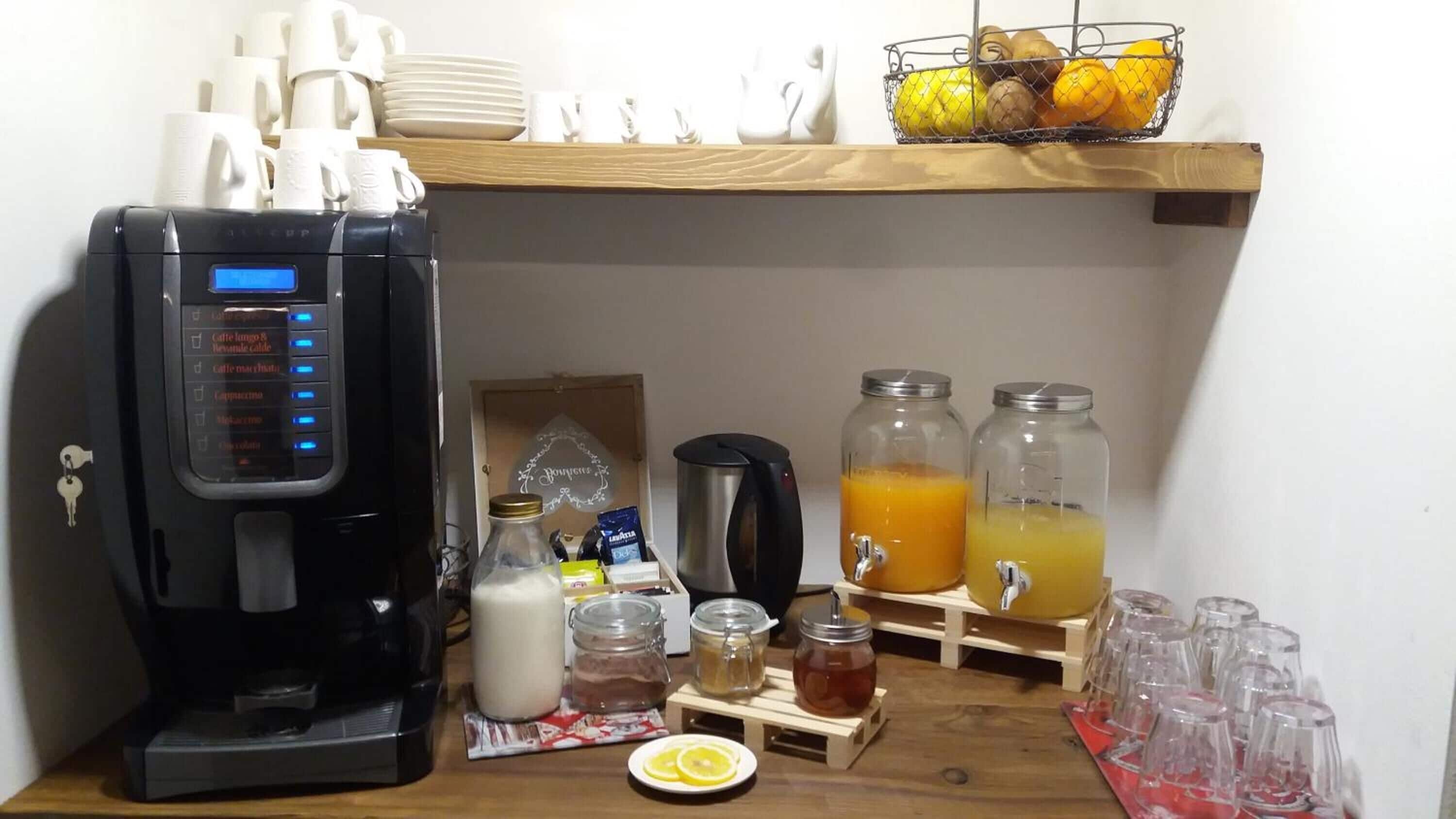 Eine Kaffeemaschine, Milch-, Tee- und Saftspender auf einer Holztischplatte.
