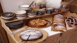 Una mesa buffet de madera con diversas opciones de repostería, como un pastel, hojaldras y una tarta.