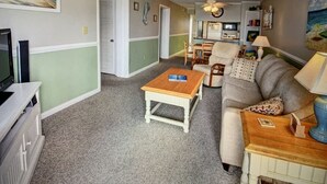 A living room with a sofa, a coffee table, a television, and a ceiling fan. - Beachfront/Pool Murrells/GardenCity/Surfside 
Wkly/MilitaryFirePoliceNurse Discs (Murrells Inlet)
