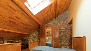 A bedroom with wooden ceiling and stone walls, a skylight, and a bed with a blue cover. - Spacious Holiday Home in Vielsalm With Garden (Vielsalm)