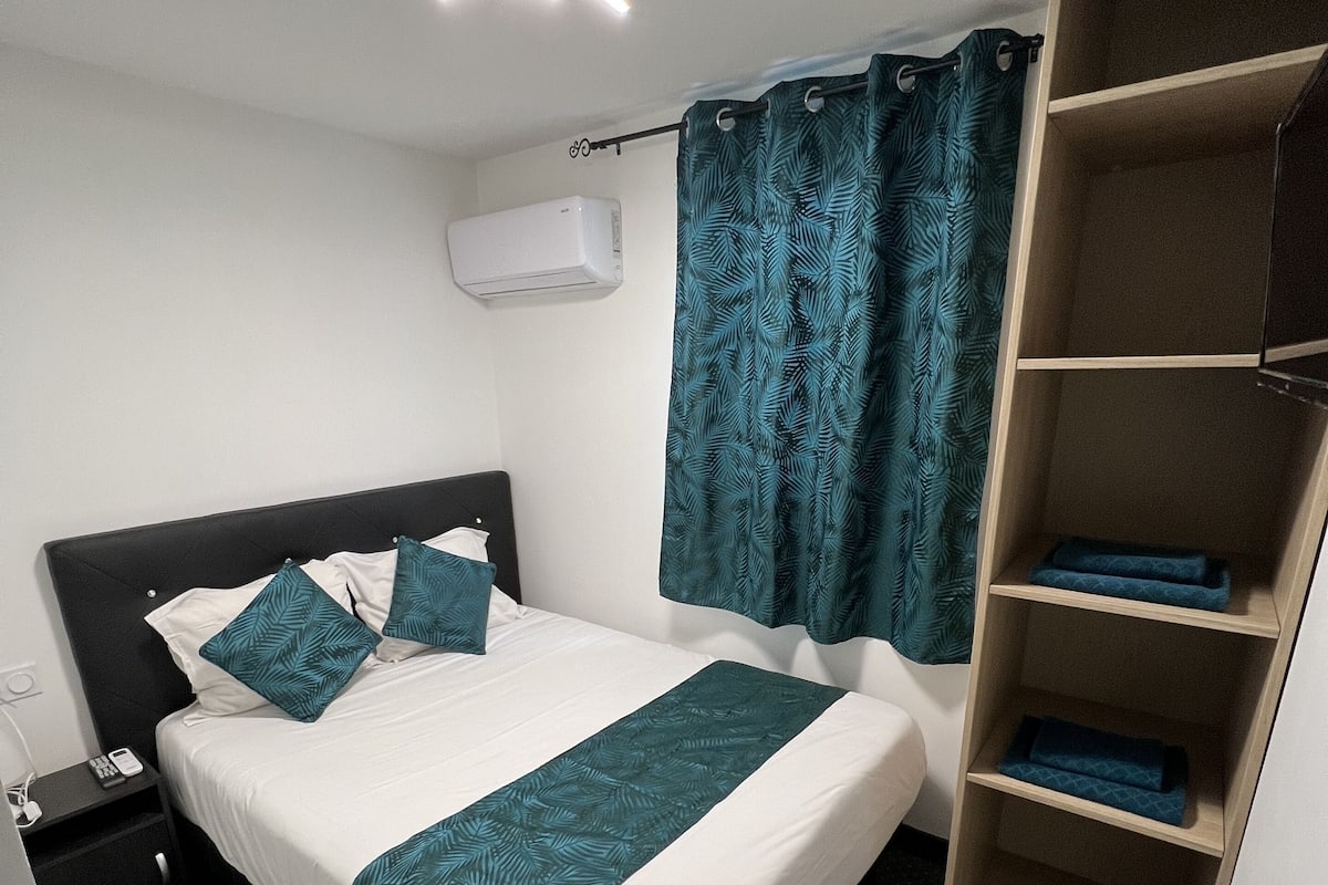A hotel room with a bed, a nightstand, a wardrobe, and a ceiling light.