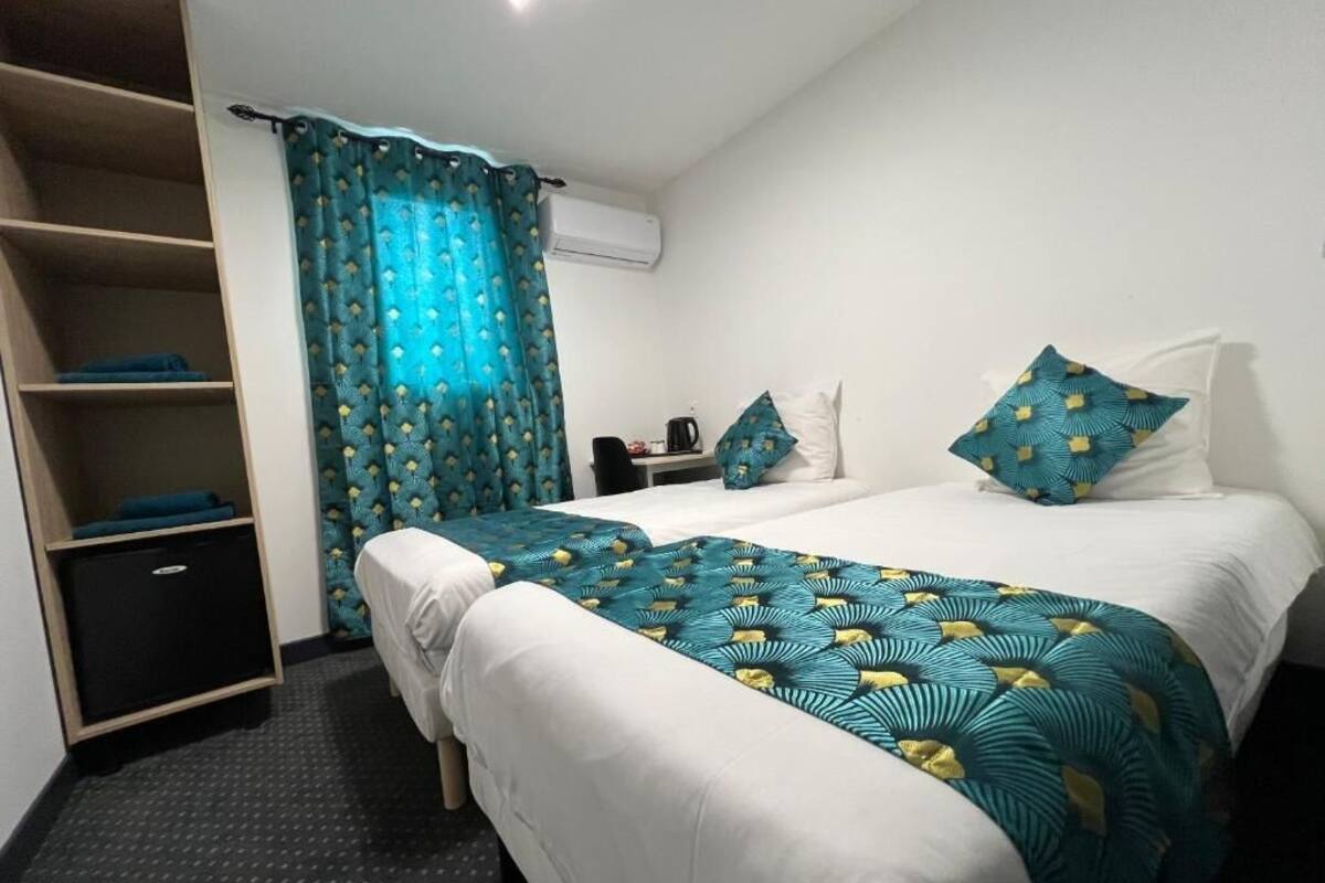A hotel room with a bed, a wardrobe, a desk, and a window with curtains.