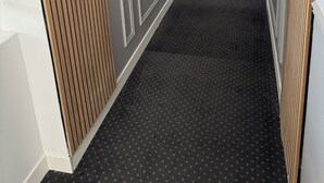 A hallway with a patterned carpet, wooden paneling on the walls, and a fire extinguisher mounted on the wall. - Hotel de la Paix Lyon Sud Givors (Givors)