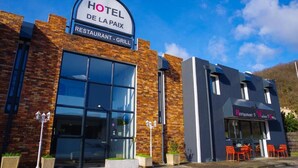 A hotel with a restaurant and grill sign, large windows, and outdoor seating with orange chairs. - Hotel de la Paix Lyon Sud Givors (Givors)
