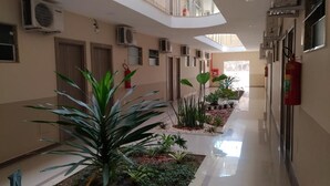 A hotel corridor with multiple doors, air conditioning units, and potted plants. - Paracambi Top Hotel (Paracambi)