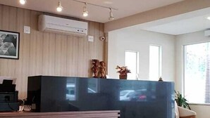 A modern living room with a wooden bench, a glass coffee table with a plant, a black hanging light fixture, and a dark-colored sofa. - Paracambi Top Hotel (Paracambi)
