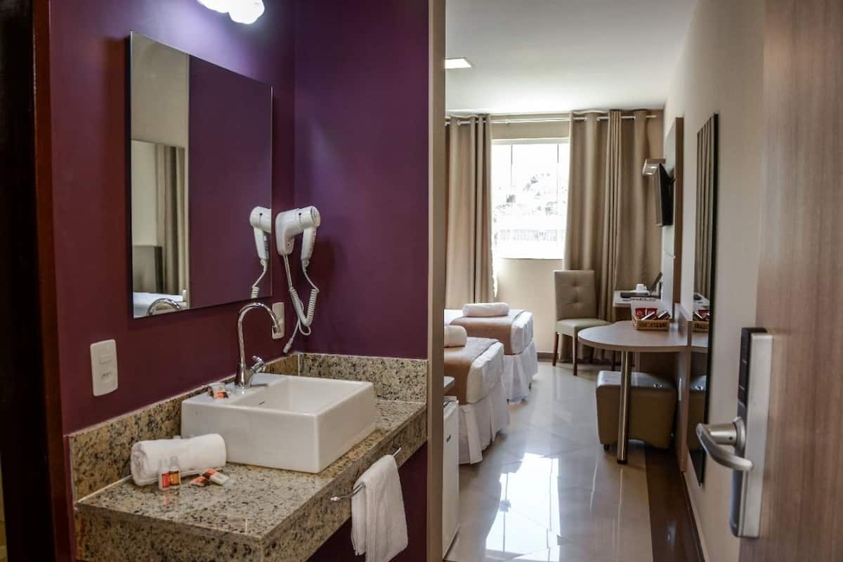 Une salle de bain d’hôtel équipée d’un lavabo, d’un miroir, d’un sèche-cheveux et d’une serviette.