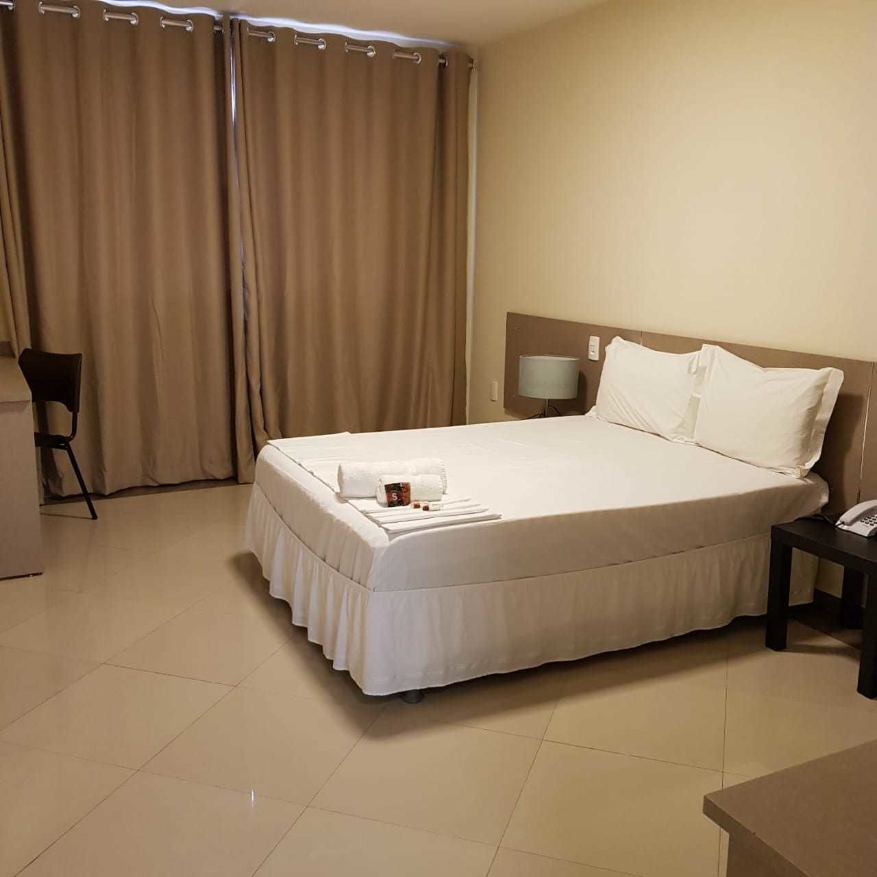 Une chambre d’hôtel avec un grand lit, une table de chevet avec une lampe, une chaise et un bureau.