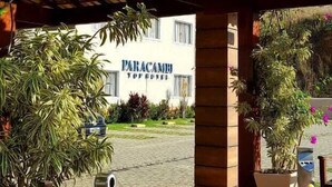 A wooden pergola with a view of a building labeled "PARACAMBI HOTEL" in the background. - Paracambi Top Hotel (Paracambi)