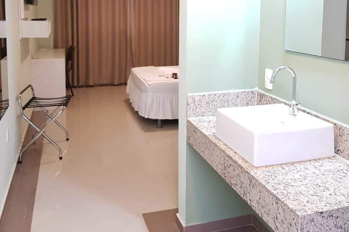 Une chambre d’hôtel comprenant un lit, un bureau et une salle de bain avec un lavabo et un miroir.