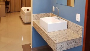 A hotel bathroom with a white sink, a large mirror, and a granite countertop. - Paracambi Top Hotel (Paracambi)