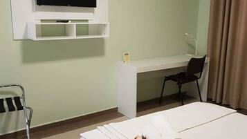 A hotel room with a bed, a desk, a chair, a television, and a sign indicating no smoking.