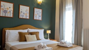 A hotel room with a bed, pillows, a bedside table with a lamp, and artwork on the wall. - Residence Ferraud (Pinerolo)