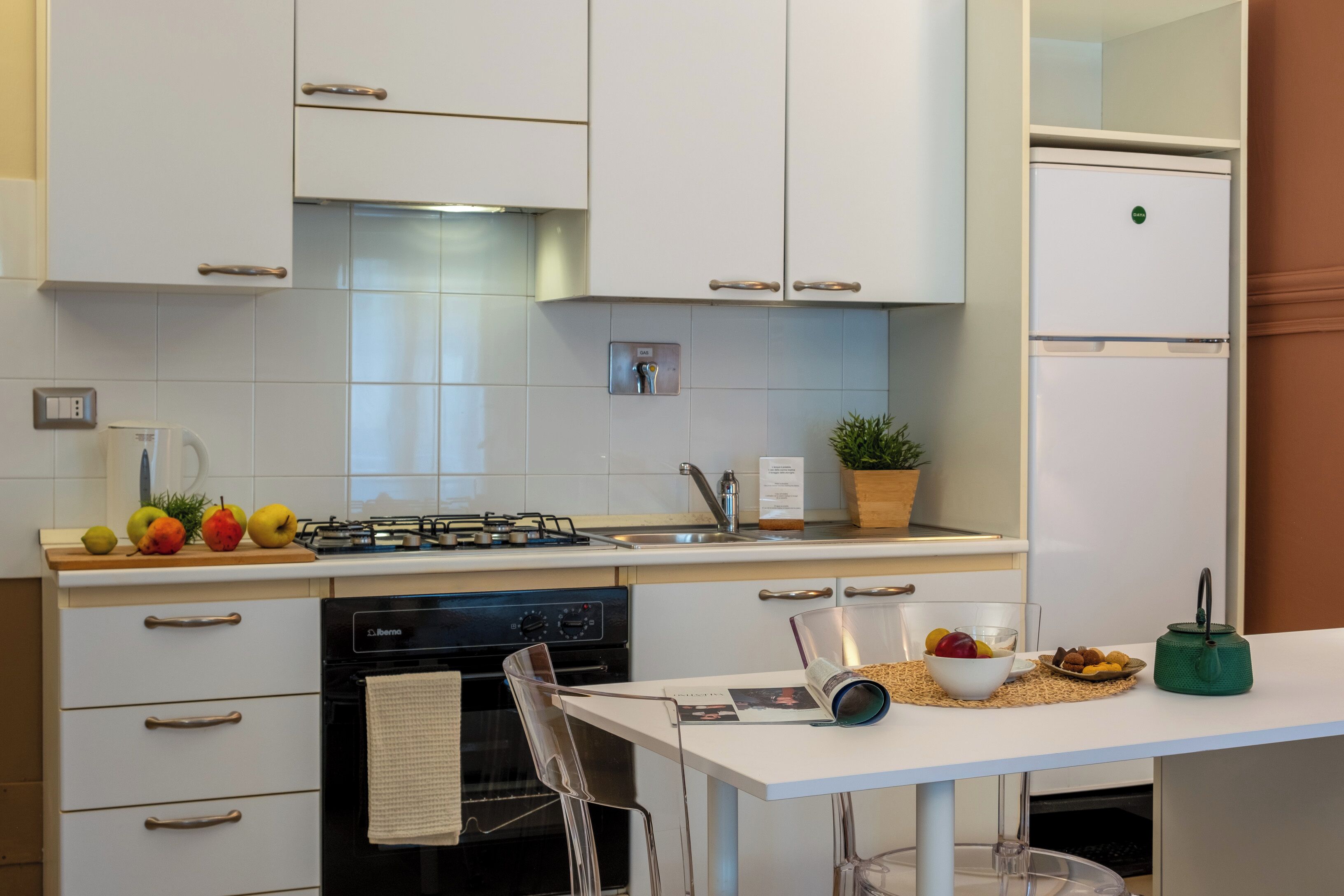 A modern kitchen with white cabinets, a gas stove, a dishwasher, and a refrigerator.