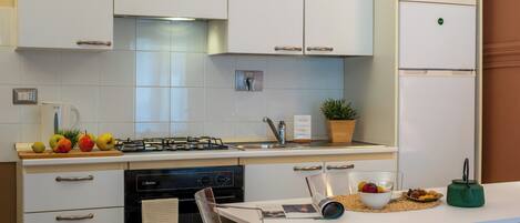 A modern kitchen with white cabinets, a gas stove, a dishwasher, and a refrigerator.