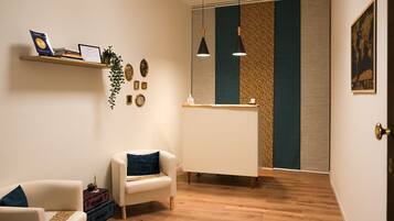 Un'accoglienza moderna con una scrivania, due poltrone, una mensola con libri e oggetti decorativi, e una parete decorata.