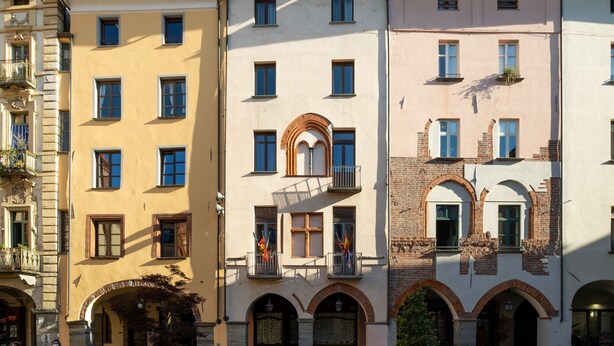 A row of multi-story buildings with balconies, arched windows, and a mix of brick and plaster facades. - Residence Ferraud (Pinerolo)