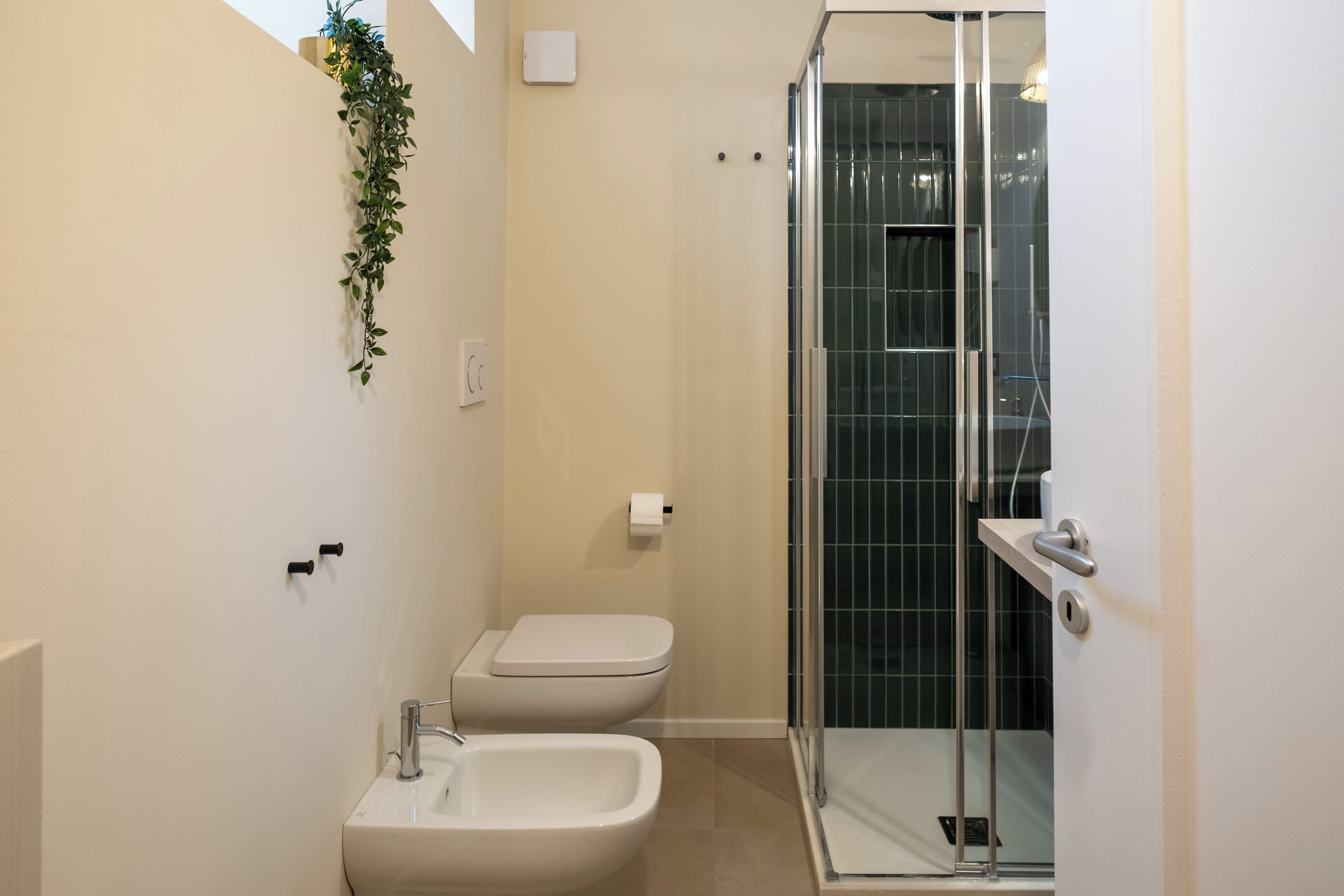 A modern bathroom with a glass-enclosed shower, a bidet, and a toilet.