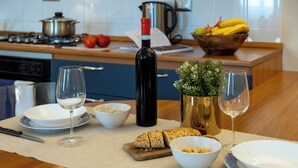 A kitchen with a dining table set for a meal, including plates, bowls, wine glasses, and a loaf of bread. - Residence Ferraud (Pinerolo)