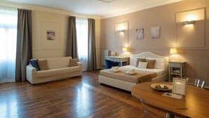A hotel room with a bed, a sofa, a dining table, and a desk. - Residence Ferraud (Pinerolo)