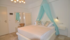 A bedroom with a bed, a nightstand, a wall-mounted light, a ceiling fan, and a door. - Nufaro Traditional Studios (Naxos)