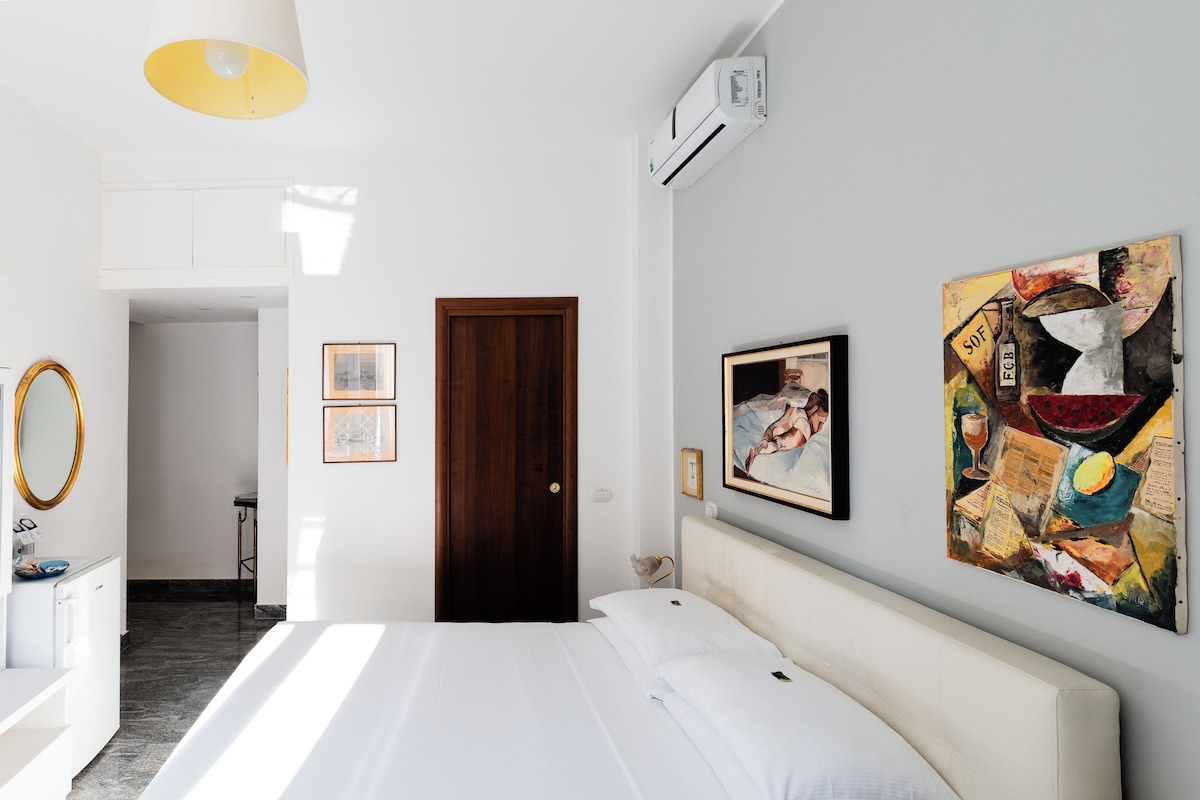 Una habitación de hotel moderna con cama, mesita de noche, espejo y aire acondicionado instalado en la pared.