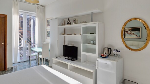 A modern hotel room with a TV, white furniture, a small fridge, and a balcony with a view. - Aiello Suites Executive (Milan)