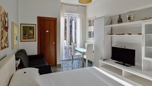 A modern hotel room with a bed, a TV, a desk, and a balcony with a view. - Aiello Suites Executive (Milan)