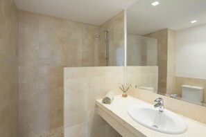 Un baño moderno con un espejo grande, un lavamanos y una ducha.