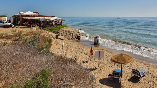 Een restaurant aan het strand met terras en uitzicht op zee.