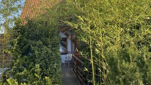 A wooden deck leading to a building with a tiled roof and solar panels. - Gästehaus Denninger (Karlsbad)