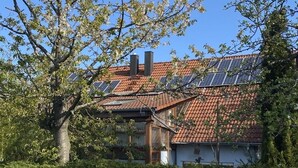 A house with a red-tiled roof, solar panels, and a chimney. - Gästehaus Denninger (Karlsbad)
