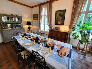 Een eethoek met een lange tafel, gedekt voor een maaltijd, omringd door stoelen.