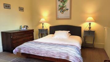 A bedroom with a bed, two bedside tables with lamps, a dresser, and a framed picture on the wall.